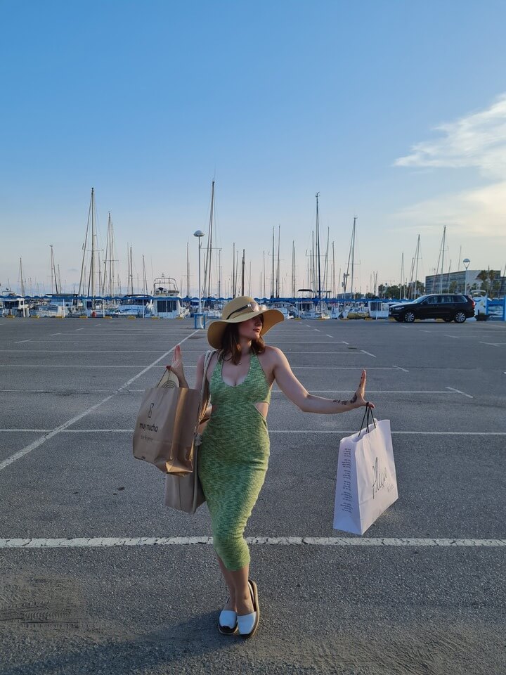 young woman posing on the docks after a day of shopping