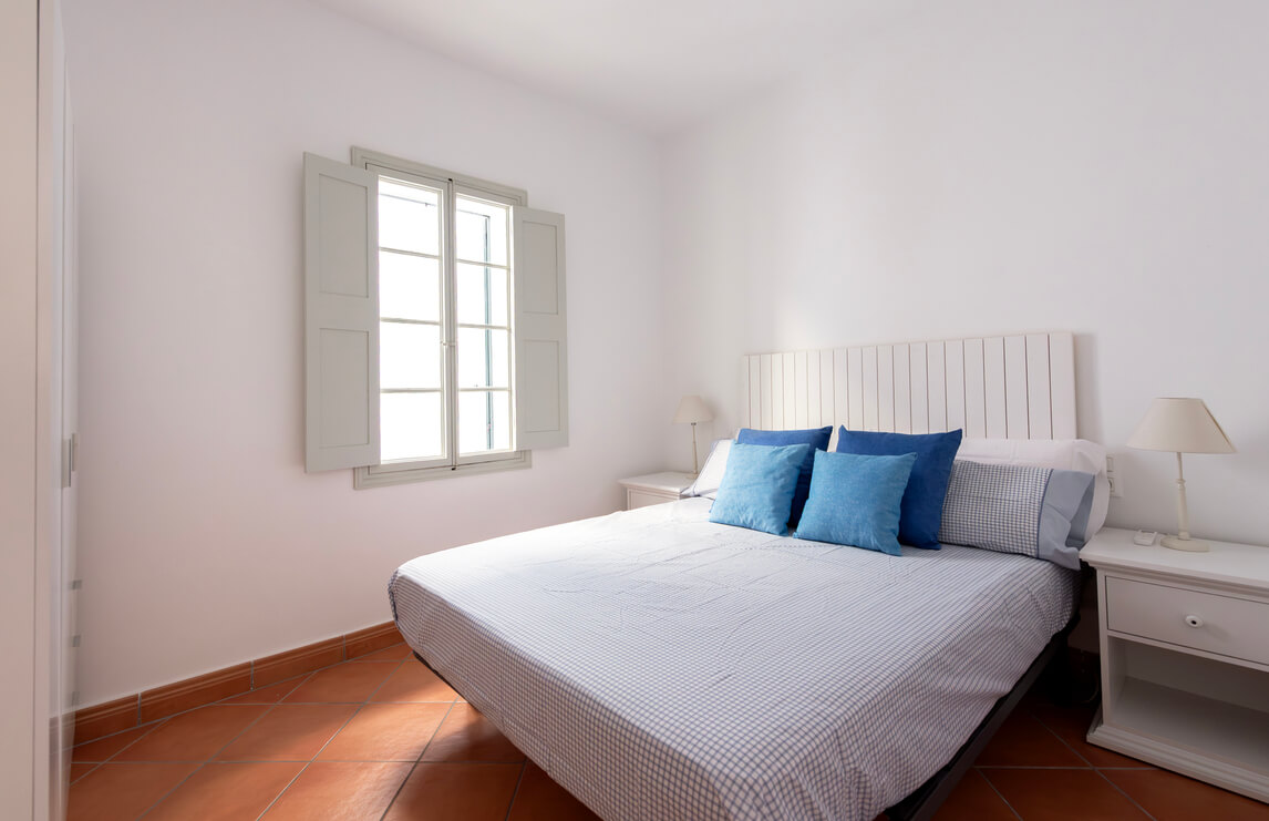 cozy bedroom with queen-size bed, warm colors, big window, in Menorca